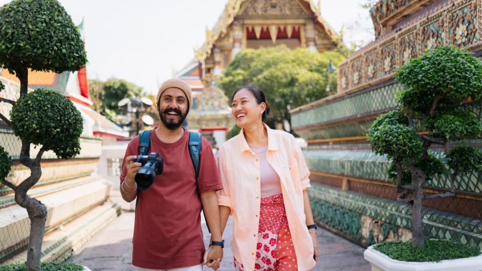 Two travellers laughing as they walk through a temple courtyard